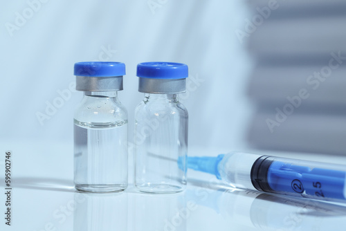 Syringes and vaccines are placed on the table in the medical office, cool toned image, blue color temperature