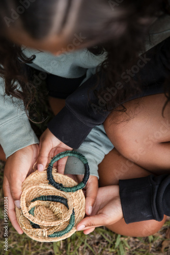 Aboriginal people sitting on grass, weaving baskets and bangles photo