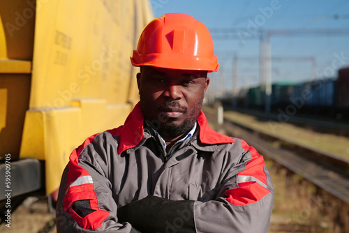 Railroad man in uniform and red hard hat look at the camera