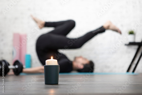 Close-up of candle with practicing yoga in lotus pose man on background. Yoga poses and stretching concept 