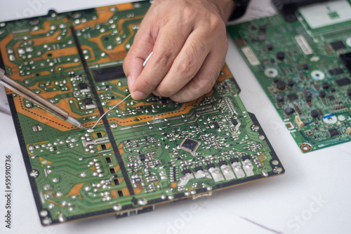 Technician using a soldering iron to repair a circuit board © vachiravit
