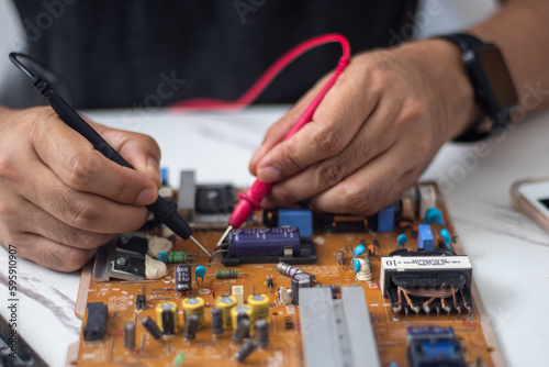 Technician using tool to measure circuit board, check and repair