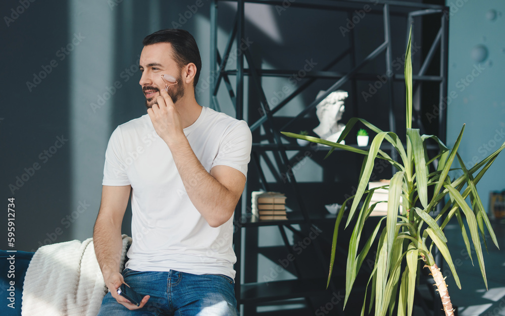 Bearded man using jade face roller for beauty facial massage therapy at home. Beauty treatment. Facial treatment, cosmetology. Facial skincare. Bearded man using jade face roller for beauty facial massage therapy at home. Beauty treatment. Facial treatment, cosmetology. Facial skincare.