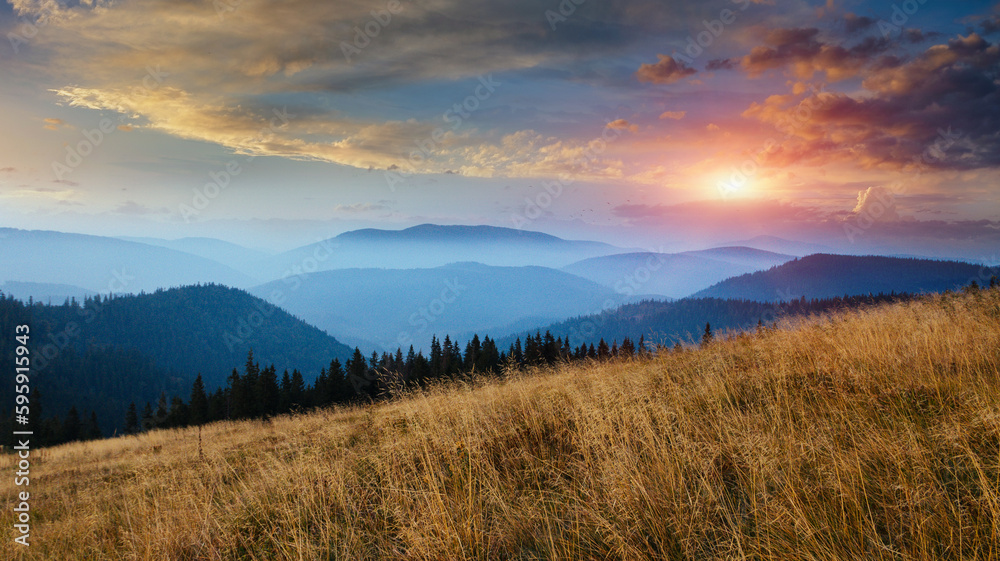 Obraz premium Amazing panoramic landscape in the mountains at sunrise. View of colorful sky and foggy hills covered by forest. Concept of the awakening wildlife.