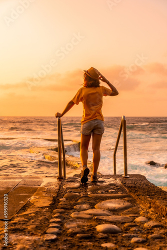 Woman strolling in the sunset in the La Maceta rock pool on the island of El Hierro en la Frontera, Canary Islands