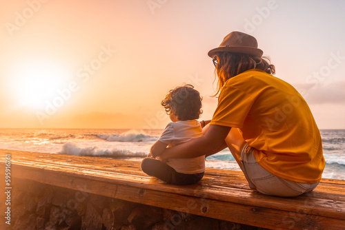 Mother and son at sunset in the natural pools of La Maceta in El Hierro, Canary Islands. sitting looking at the sea © unai