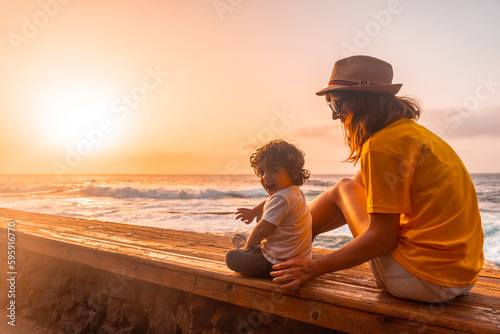 Mother and son at sunset in the natural pools of La Maceta in El Hierro, Canary Islands. sitting looking at the sea © unai