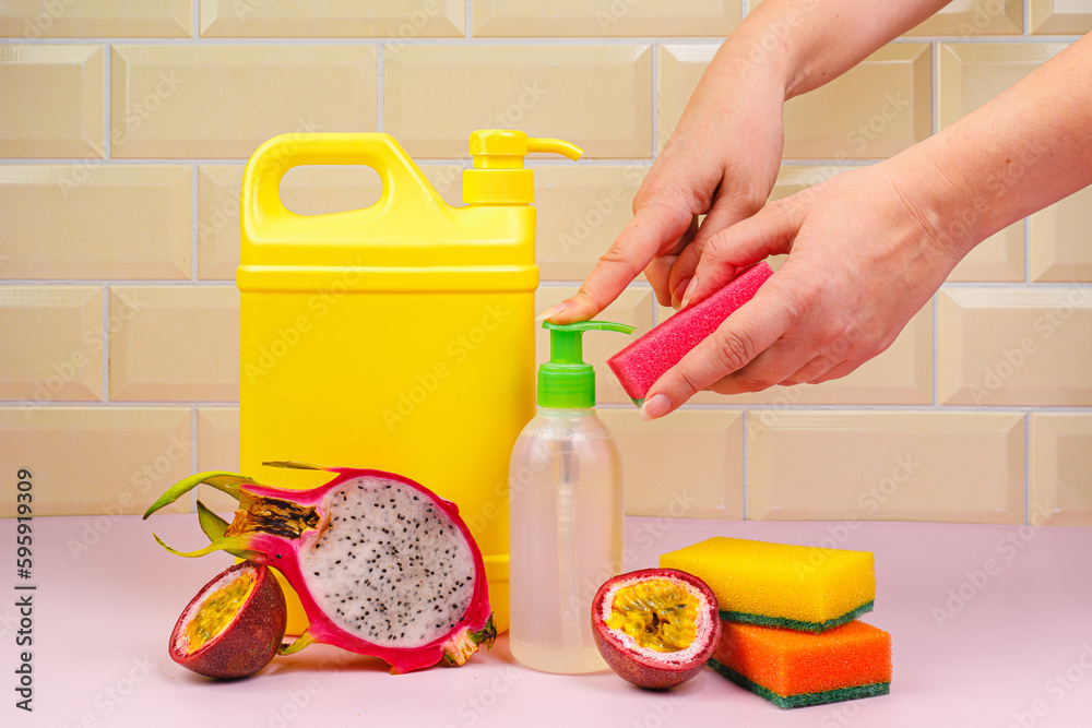 Pouring dishwasher liquid onto a kitchen sponge. Dishwashing liquid