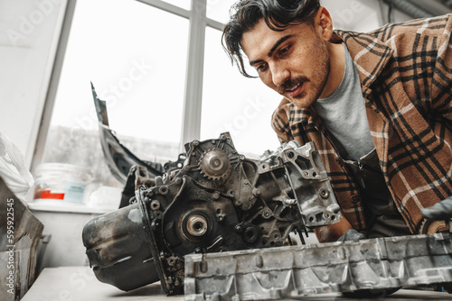 Workman disassembling car engine at the working table of the car service garage