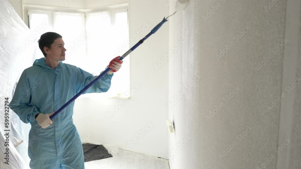 Man paints the wall with a roller Man paints the wall with a roller
