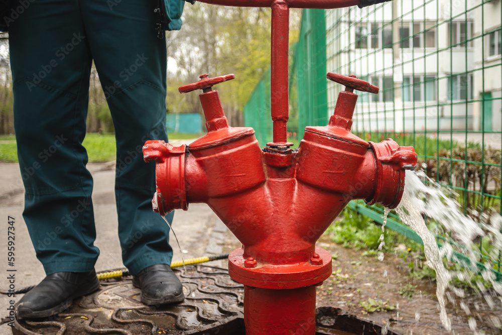 Leaking fire hydrant water flow and unrecognizable firefighter Stock Photo Adobe Stock