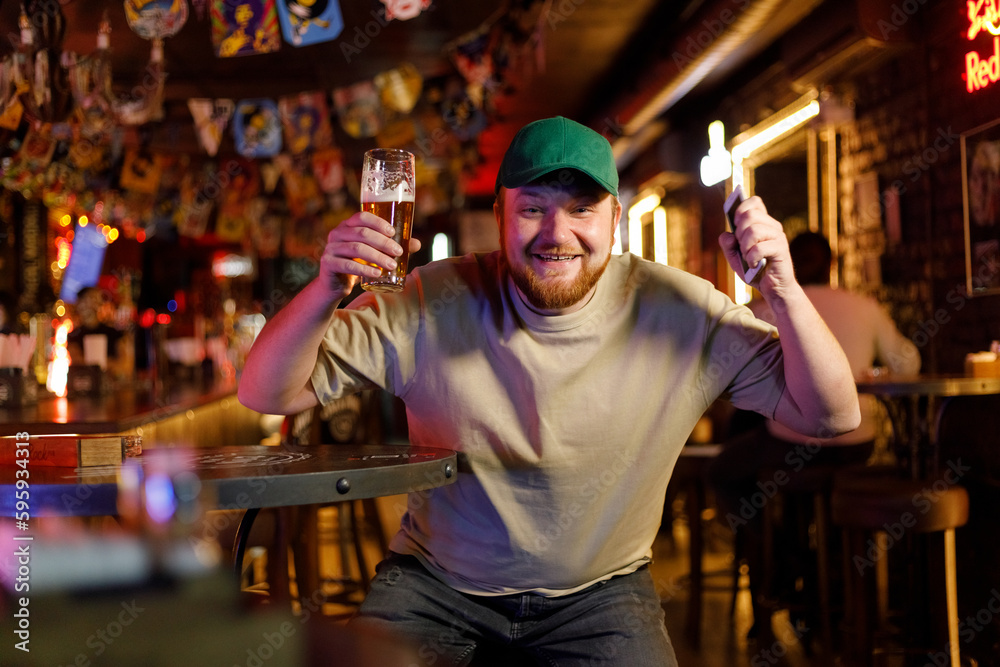 Portrait of a smiling man raising his beer glass in a pub