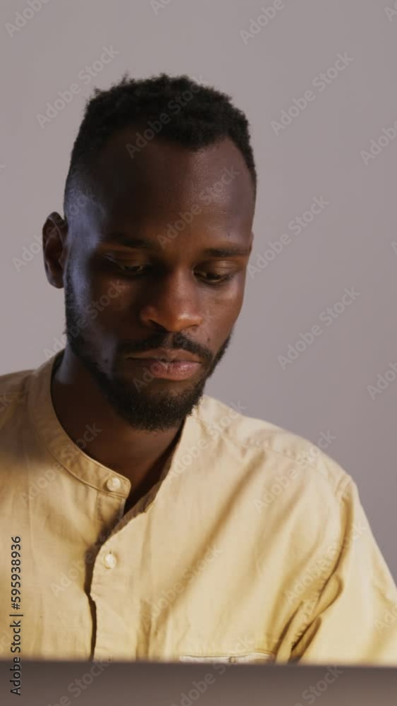 black guy with a beard in a light shirt with a short afro hairstyle typing on a laptop in an office under under the light of a table lamp black guy with a beard in a light shirt with a short afro hairstyle typing on a laptop in an office under under the light of a table lamp