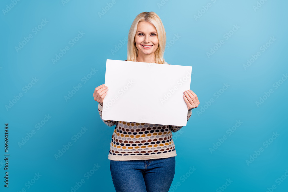 Naklejka premium Photo of positive pretty girl wear sweater rising white billboard empty space isolated blue color background