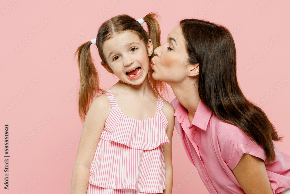 Happy smiling cheerful fun cool woman wear casual clothes with child kid girl 6-7 years old. Mother kissing daughter, looking camera isolated on plain pastel pink background Family parent day concept Happy smiling cheerful fun cool woman wear casual clothes with child kid girl 6-7 years old. Mother kissing daughter, looking camera isolated on plain pastel pink background Family parent day concept