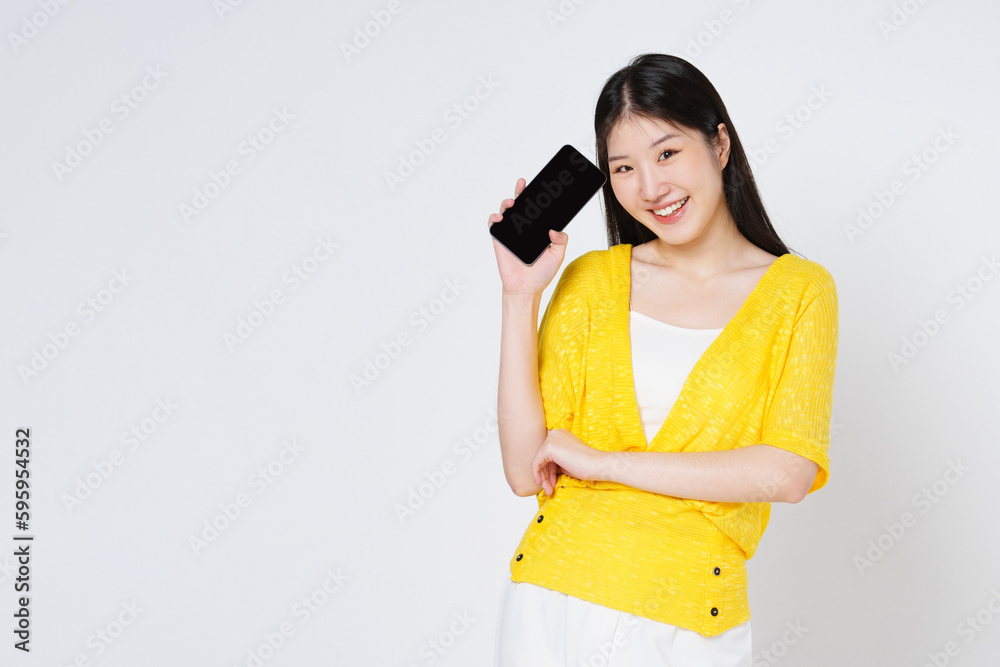 Smiling asian woman holding mobile phone while standing isolated over white background. Smiling asian woman holding mobile phone while standing isolated over white background.