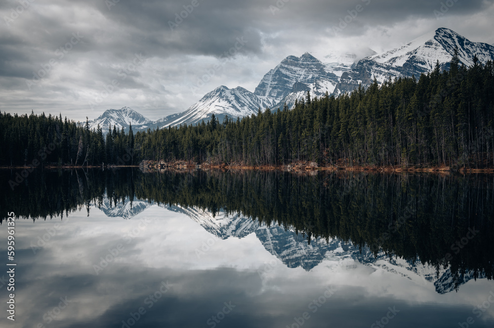 Herbert lake in Alberta, Canada on a cloudy day with stunning mountains and water reflections