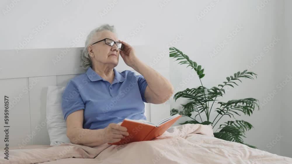 Sudden headache in an elderly woman lying in bed reading a book Sudden headache in an elderly woman lying in bed reading a book