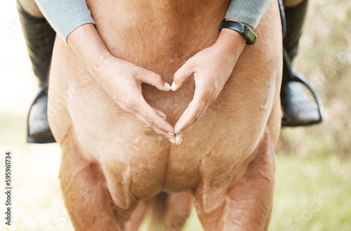 The connection is undeniable. a unrecognizable female making a heart shape with her hands while sitting on a horse outside.