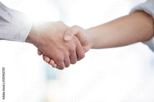 A reassuring hand in a time of doubt. two unrecognizable businesspeople shaking hands in a modern office.