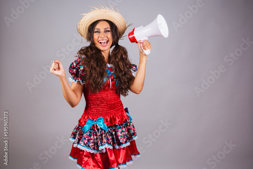 Brazilian woman, with June party clothes. Saint John's festival. with megaphone shouting and announcing discounts and promotion. photo