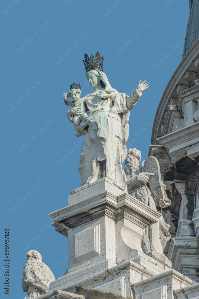 Ancient sculpture of beautiful Venetian Noble Renaissance Era woman with child at Basilica di Santa Maria della Salute in Venice, Italy, at blue sky