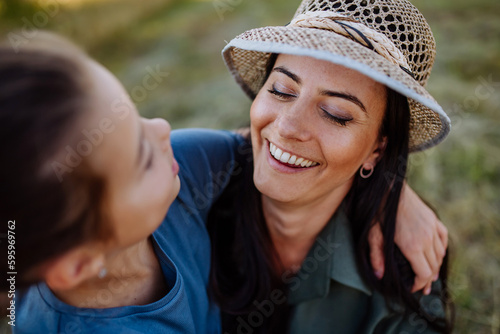 Portrait of happy, affectionate mother and daughter hugging during sunset.