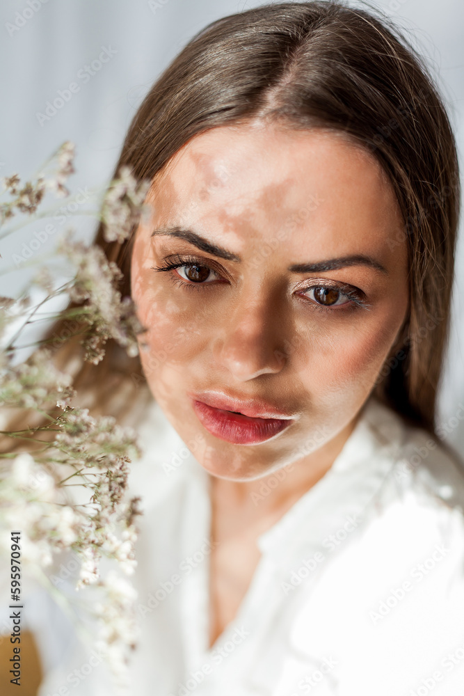 Portrait of beautiful young woman with long hair on white background with dried flowers. Shadow on the face from flowers. Spring.