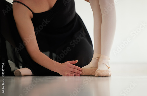 Learning the correct techniques. Closeup shot of a ballet teacher assisting a student with her position in a dance studio.