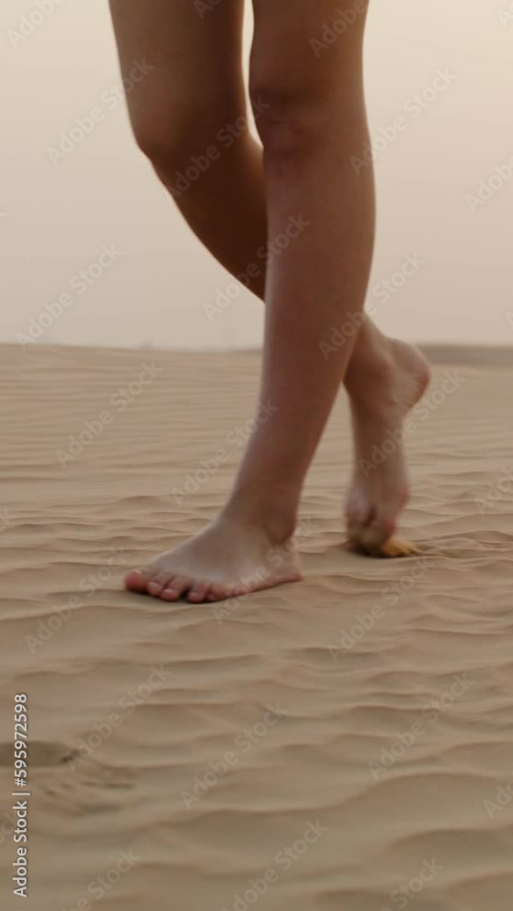 A young woman in shorts smiles walking on the sand in the desert near the road, the wind is blowing her curly hair A young woman in shorts smiles walking on the sand in the desert near the road, the wind is blowing her curly hair