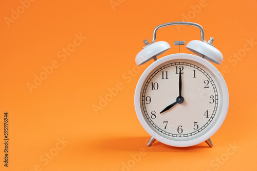 Retro alarm clock on orange table background, vintage style, flat lay