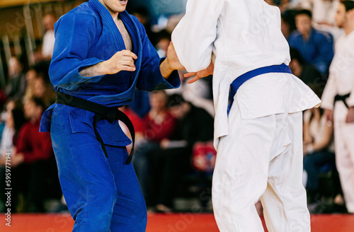 judoists athlete wrestling in white and blue kimono, judo fight championship
