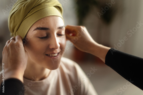 Somebody giving sfarf on head to young woman with cancer  concept of support.