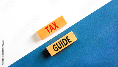 Tax guide symbol. Concept words Tax guide on beautiful wooden block. Beautiful white and blue background. Business and Tax guide concept. Copy space.