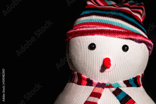 A snowman in a striped hat and scarf on a black background