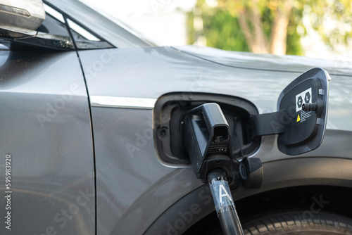 CCS2 DC charger socket head is plugging with EV car for recharging the energy. Transportation and technology concept scene, selective focus at hand part. 