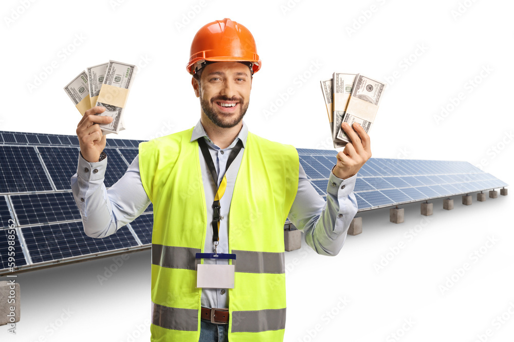 Male engineer with a safety vest and hardhat holding stacks of money in front of photovoltaic field Male engineer with a safety vest and hardhat holding stacks of money in front of photovoltaic field