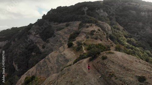 4K drone footage over woman running thorugh mountain ridge with huge panoramic landscape on the back, La Mola, Catalonia, Spain.
Mid angle, parallax movement. photo