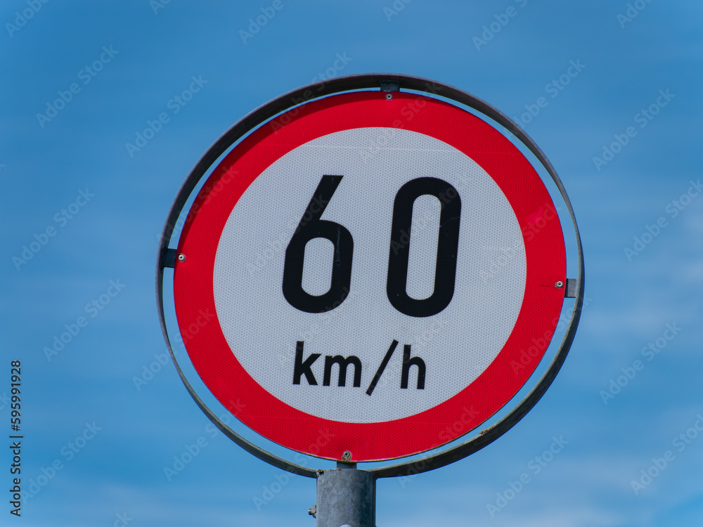 A road sign limiting the speed to 60 km h on a blue sky background. A road sign limiting the speed to 60 km h on a blue sky background.