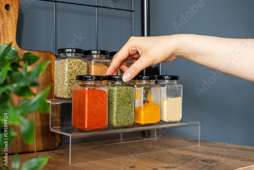 Fototapeta Naklejka Na Ścianę i Meble -  Cropped hand holding jar of spices on kitchen.