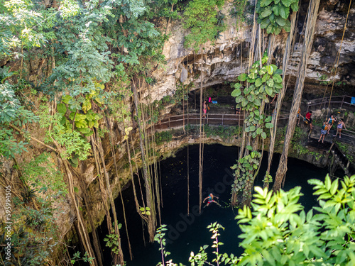 Cenote, lush vegetation, rocks and deep blue water photo