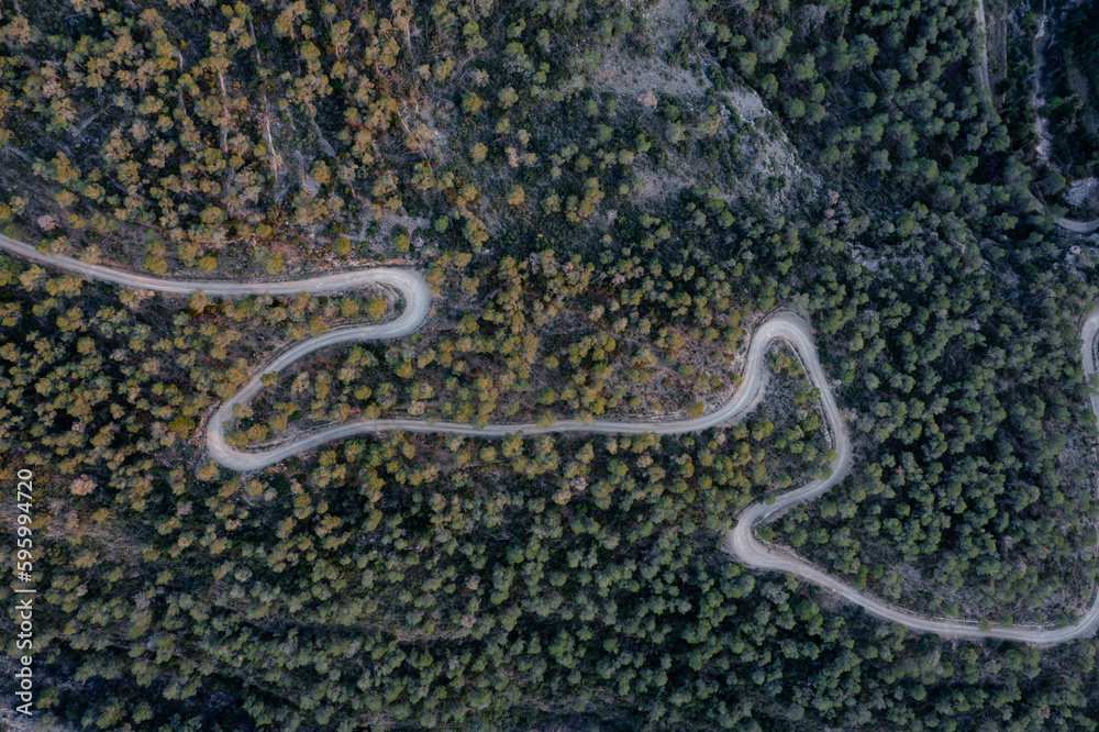 Aerial shot of a curvy road on a mountain in a forest
