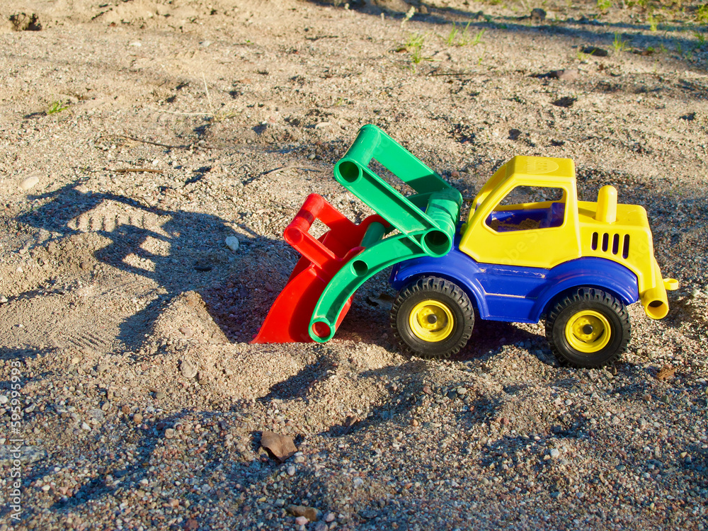 Plastic toy truck with its shadow in the sandbox at childrens playground outdoors in summer. Plastic toy truck with its shadow in the sandbox at childrens playground outdoors in summer.