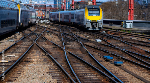 Panorama of railway infrastructure with two trains arriving at Brussels main station, Belgium. Network of tracks, switches overhead lines and multiple units on a sunny day in european metropole.
