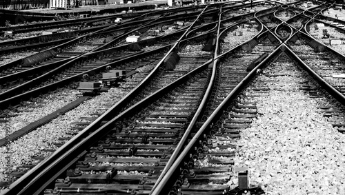 Railway tracks with switches and interchanges at a main line station in Bruxelles Midi Belgium with geometrical structures, thresholds, gravel and screws. Reflecting symmetrical rails black and white.