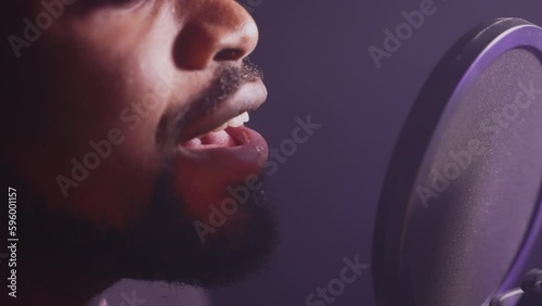 bearded african american man is singing romantic song, closeup view of mouth and professional mic photo