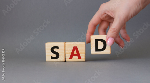 Sad symbol. Wooden cubes with words Sad. Businessman hand. Beautiful grey background. Business and Sad concept. Copy space.