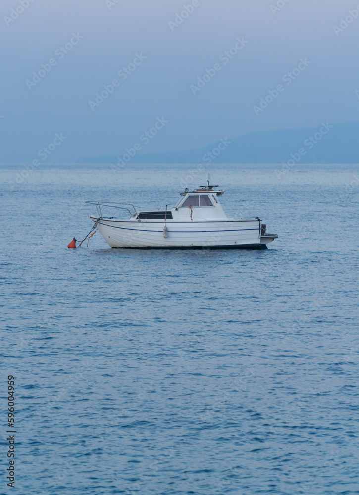 beautiful blue mediterranean sunset with and small white anchored fishing boat
