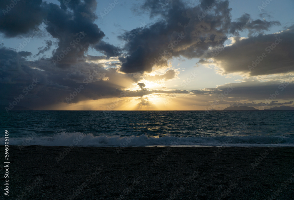 Obraz premium Beautiful and relaxing sunset at milazzo beach with cloudy blue sky and mediterranean sea