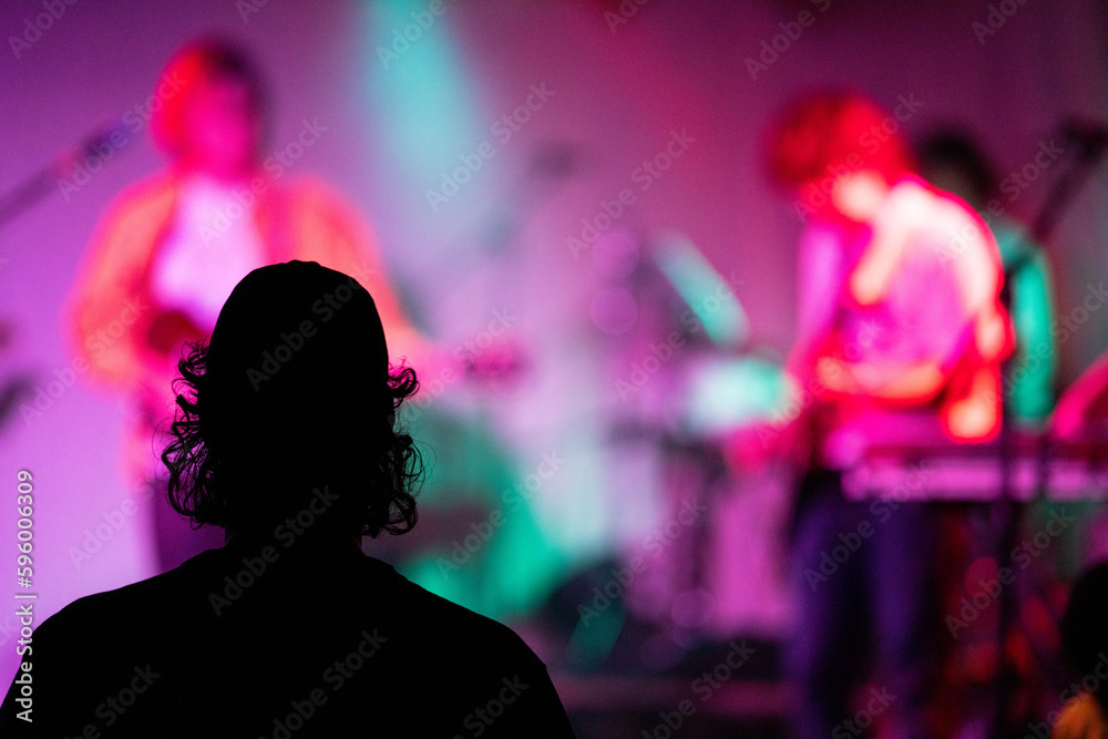 Band playing music and a gig in a venue, close up of a rock band playing guitars and instruments.